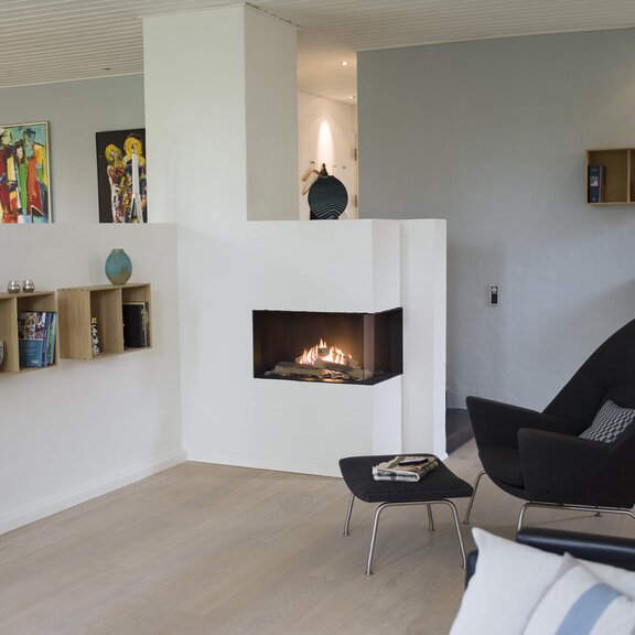 Gas-Kamin VISIO 70 RC steht als Eckkamin rechts im Eingangsbereich einer künstlerischen Wohnung und steht so im Zentrum verschiedener Teilräume